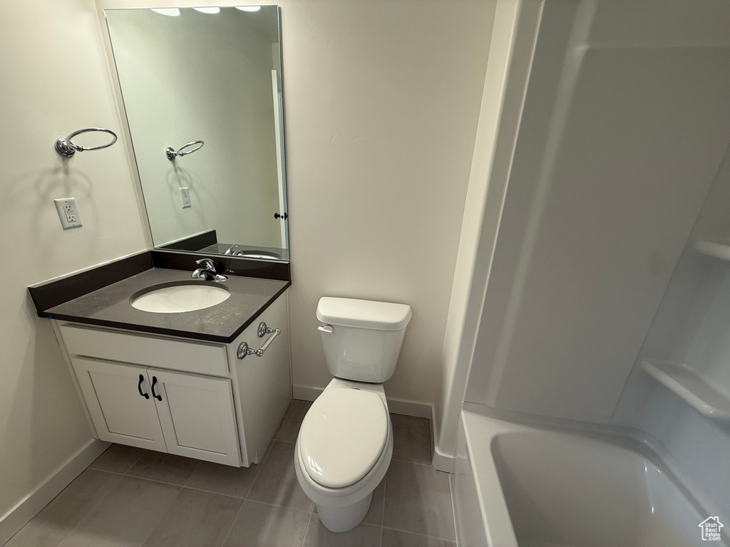 Bathroom with toilet, vanity, tile patterned flooring, and baseboards