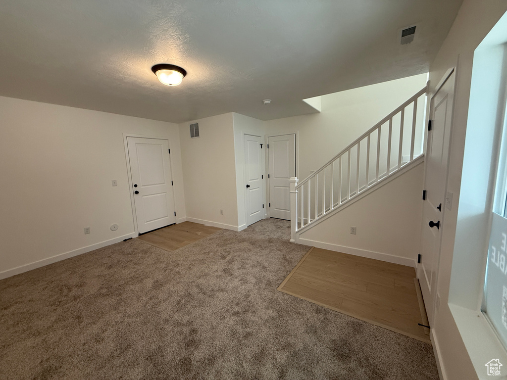 Carpeted spare room with stairway and baseboards