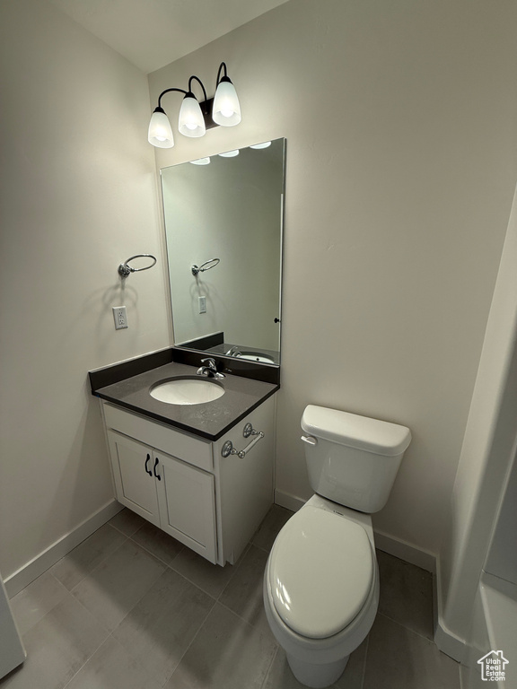 Bathroom with vanity, toilet, baseboards, and tile patterned flooring