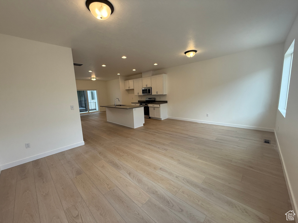 Kitchen featuring stainless steel appliances, dark countertops, open floor plan, baseboards, and recessed lighting