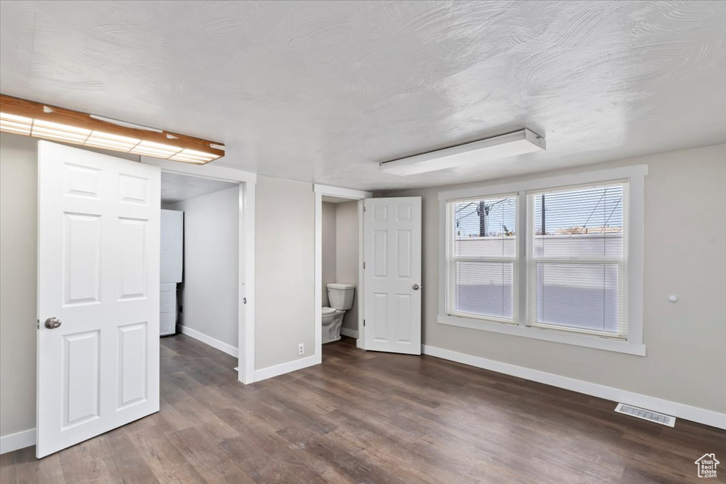 Unfurnished bedroom with wood finished floors, visible vents, and baseboards