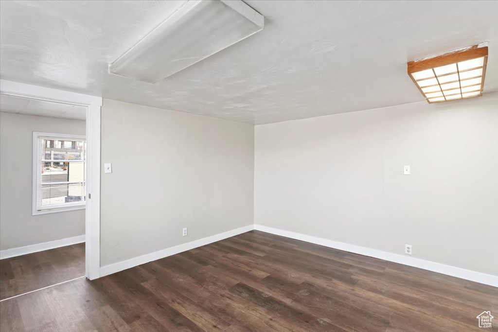 Unfurnished room with baseboards and dark wood-type flooring