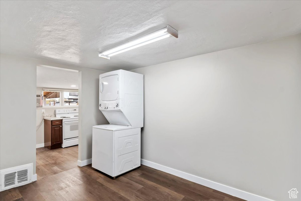 Washroom featuring stacked washing maching and dryer, laundry area, baseboards, and visible vents