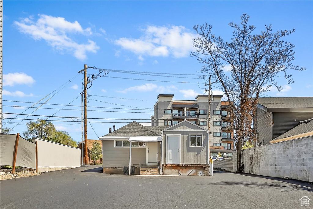View of front facade with roof with shingles and fence