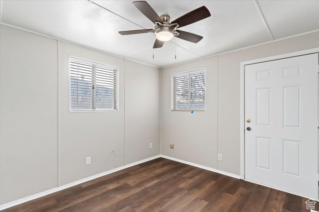 Unfurnished room with baseboards, ceiling fan, and dark wood-type flooring