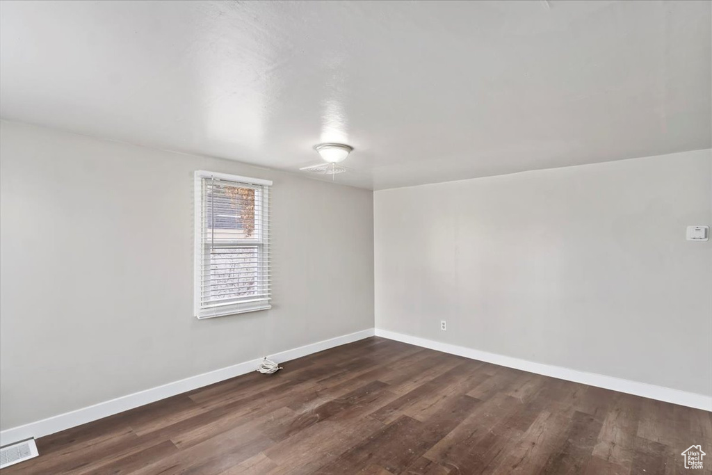 Spare room with dark wood-style flooring, baseboards, and visible vents
