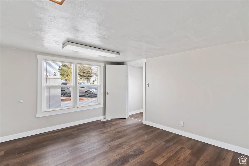 Empty room featuring baseboards and dark wood finished floors