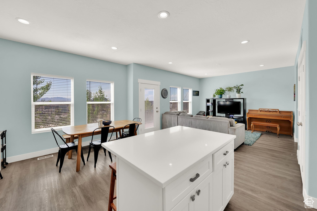 Kitchen featuring light wood-style floors, recessed lighting, white cabinetry, a kitchen island, and baseboards