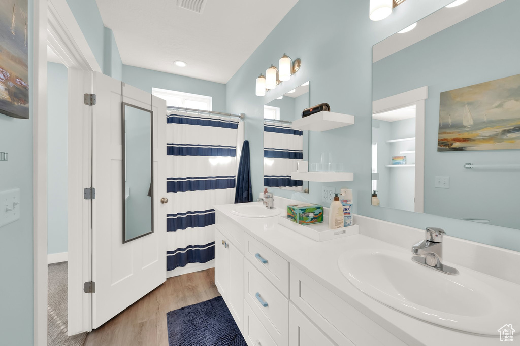 Bathroom featuring wood finished floors, double vanity, a shower with curtain, and recessed lighting