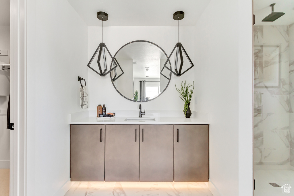 Bathroom featuring vanity, a marble finish shower, and baseboards
