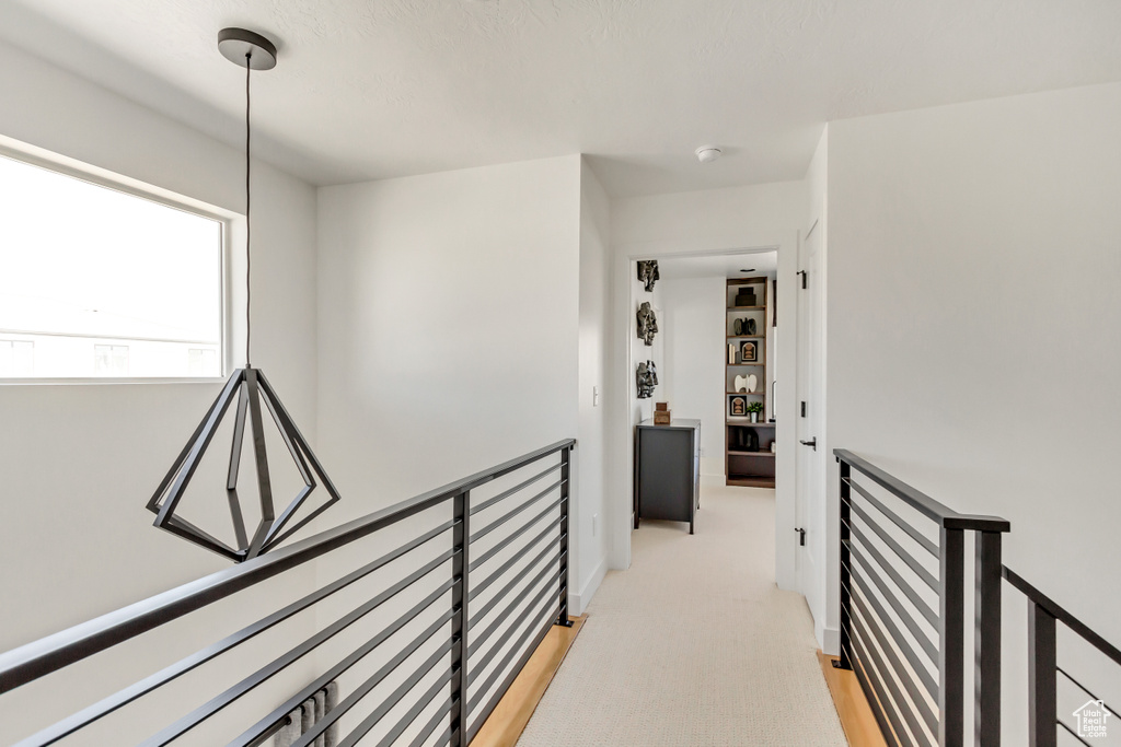 Hallway with an upstairs landing and light colored carpet