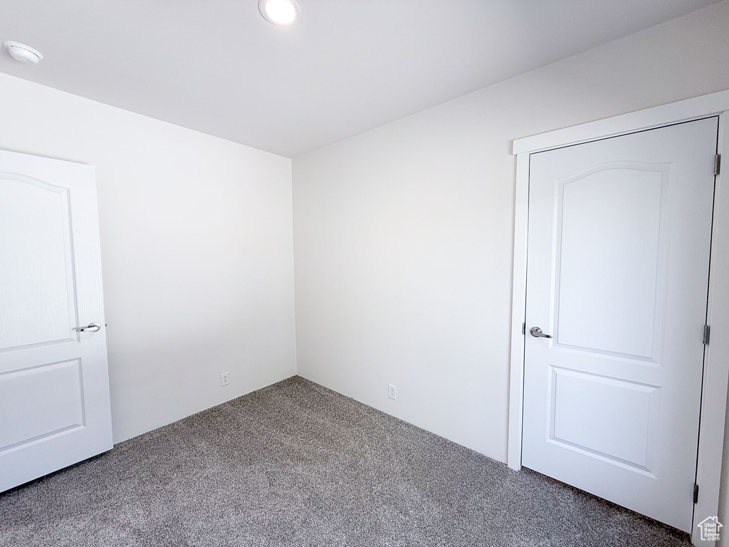 Carpeted empty room featuring a smoke detector and recessed lighting