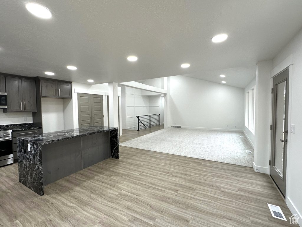 Kitchen featuring stainless steel appliances, light wood-type flooring, dark stone counters, and recessed lighting
