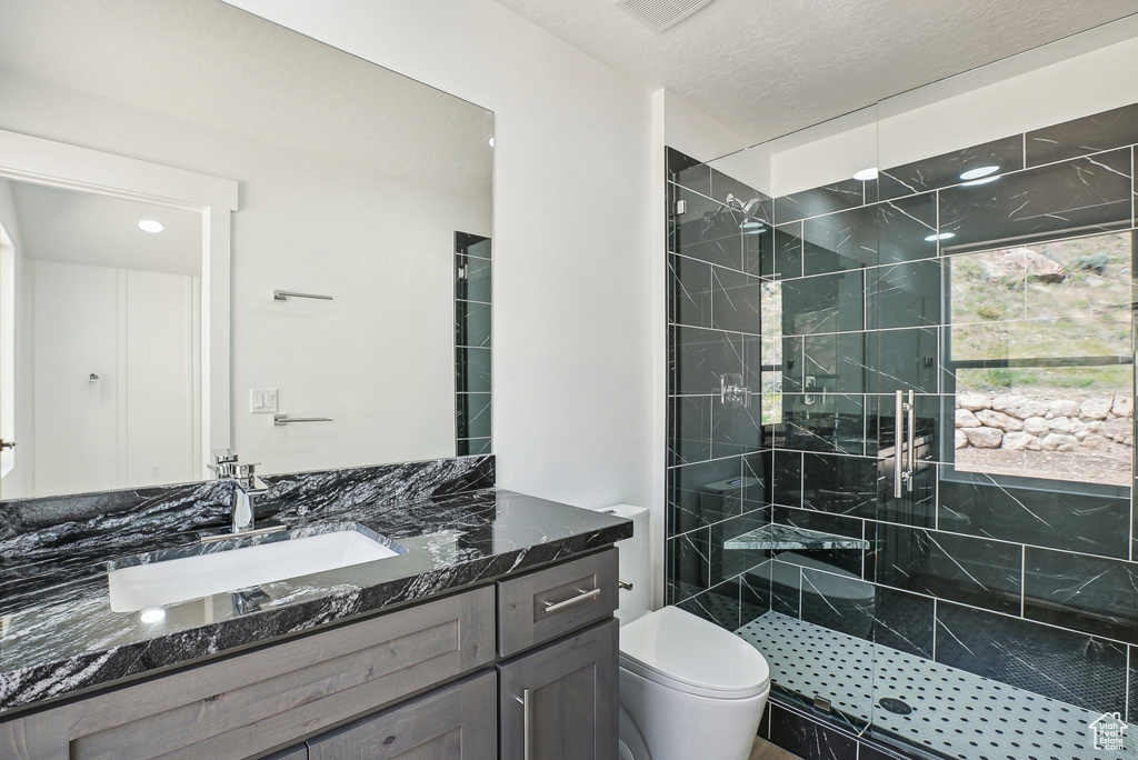 Bathroom featuring a stall shower, vanity, and toilet