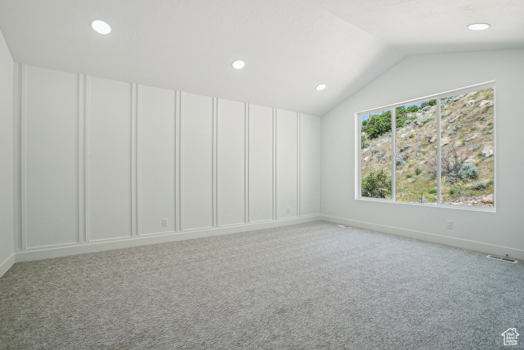 Empty room with light colored carpet, vaulted ceiling, recessed lighting, and baseboards