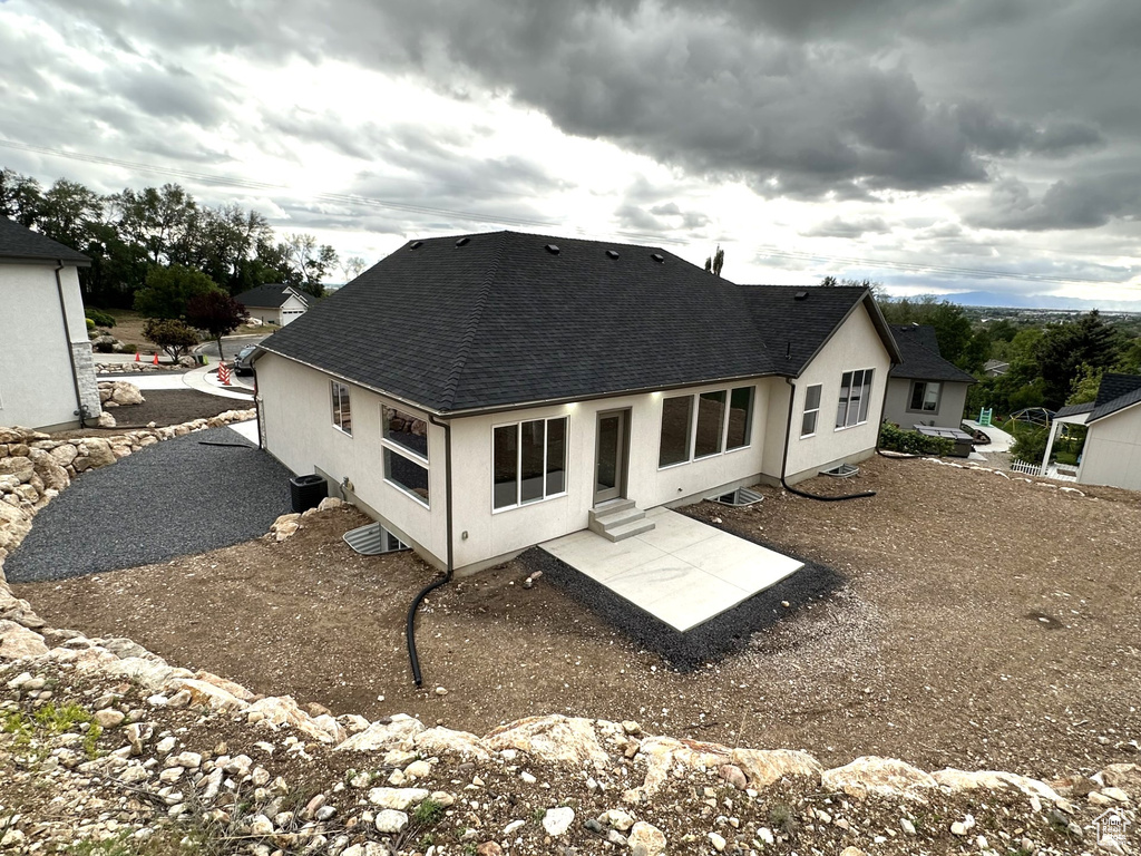 Rear view of property with roof with shingles, a patio area, stucco siding, and entry steps
