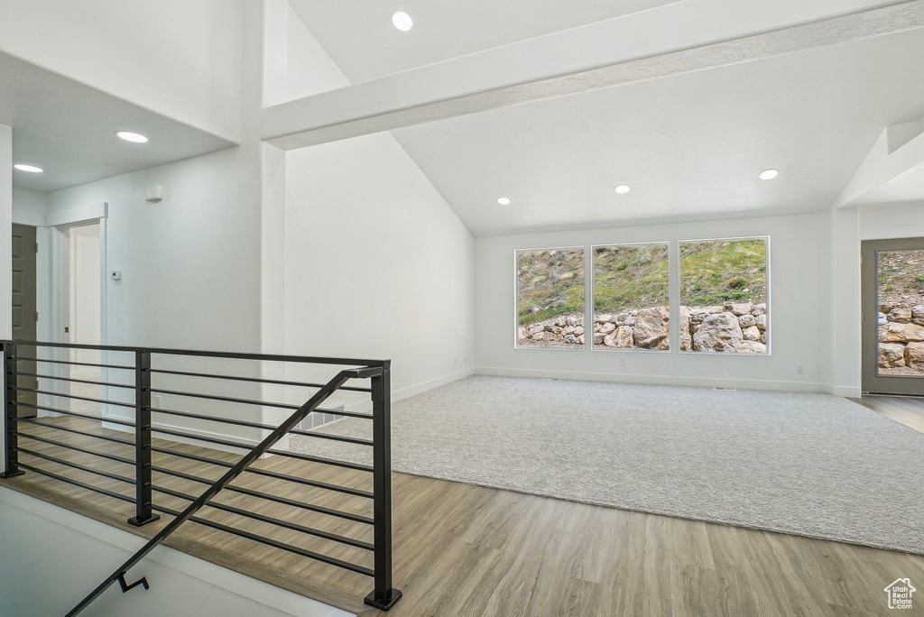 Empty room featuring wood finished floors, baseboards, vaulted ceiling, and recessed lighting