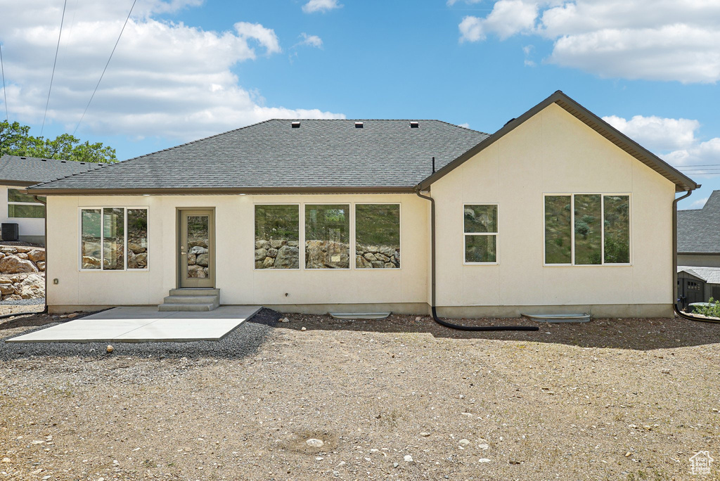 Rear view of house with a shingled roof, a patio, stucco siding, and entry steps