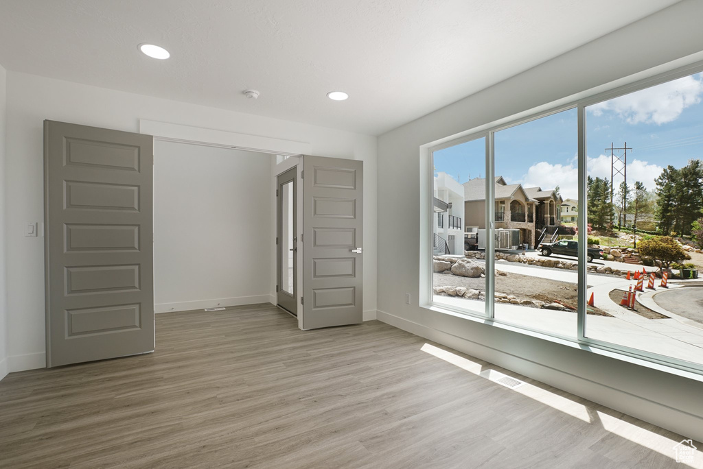 Unfurnished room with light wood-style floors, baseboards, recessed lighting, and a smoke detector