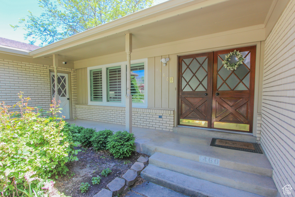 Entrance to property featuring brick siding, covered porch, and board and batten siding