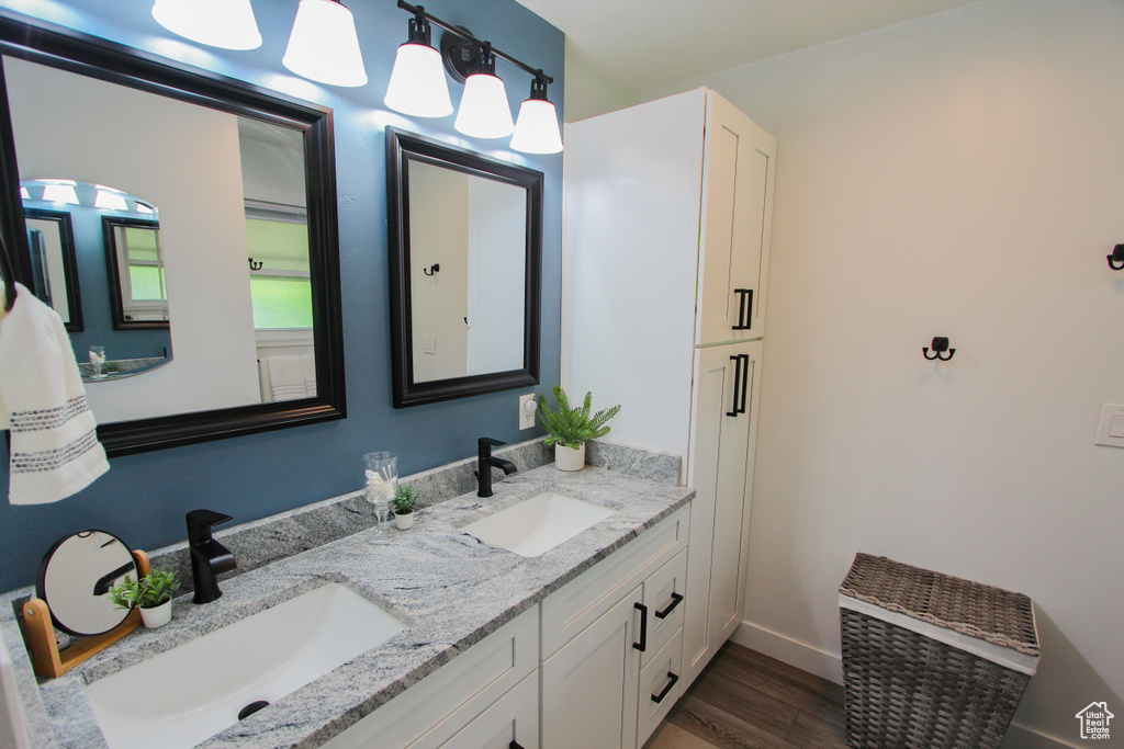 Full bath with double vanity, wood finished floors, and baseboards