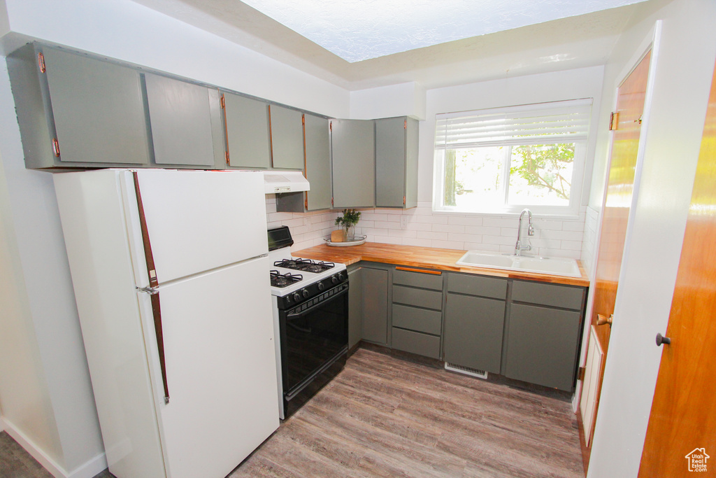 Kitchen with freestanding refrigerator, gas range oven, a sink, and gray cabinets
