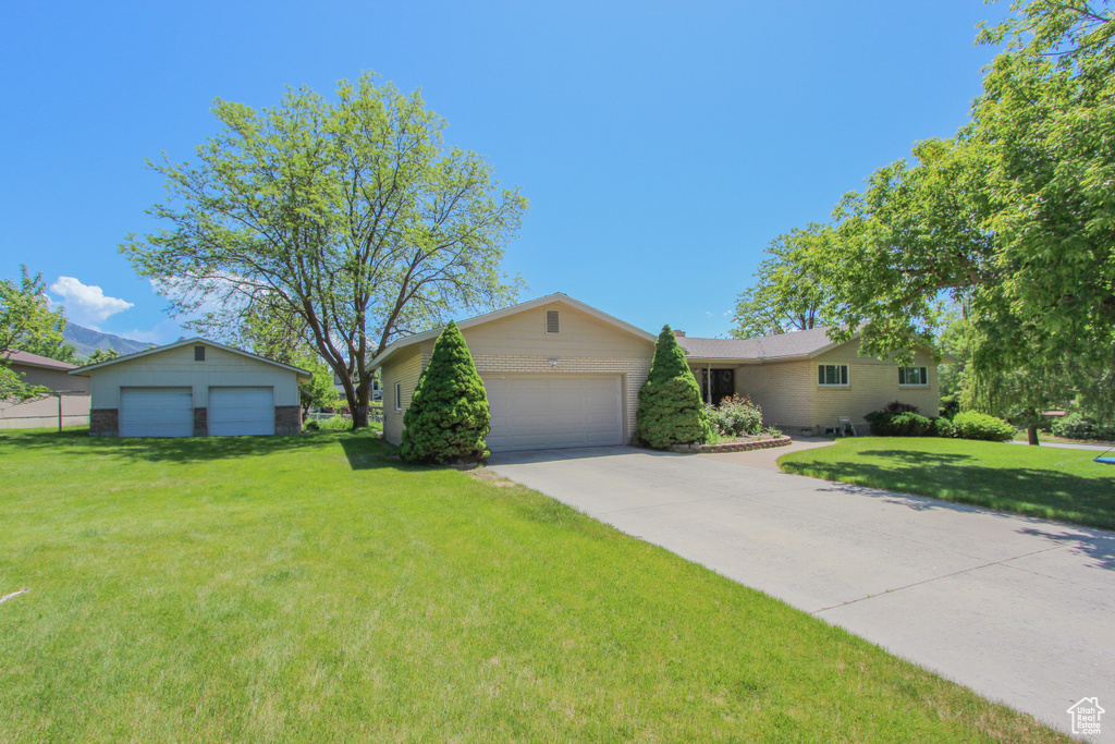 Ranch-style home with a front lawn, brick siding, an attached garage, and driveway