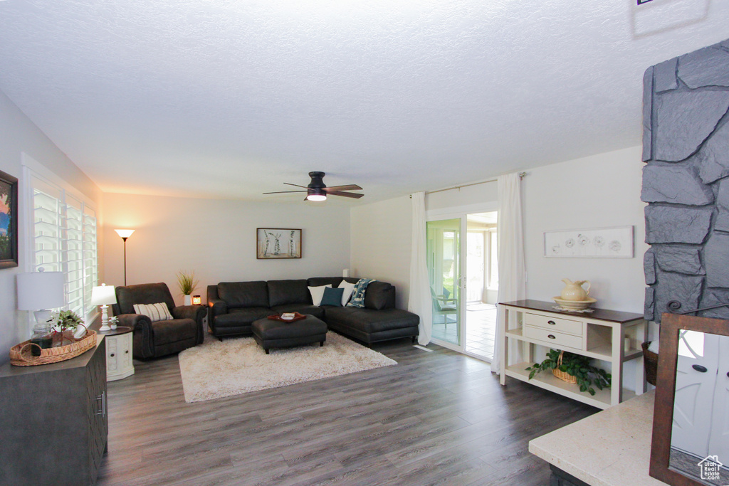 Living room with dark wood-type flooring, a ceiling fan, and a textured ceiling