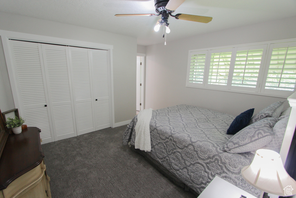 Bedroom featuring dark colored carpet, a closet, and ceiling fan