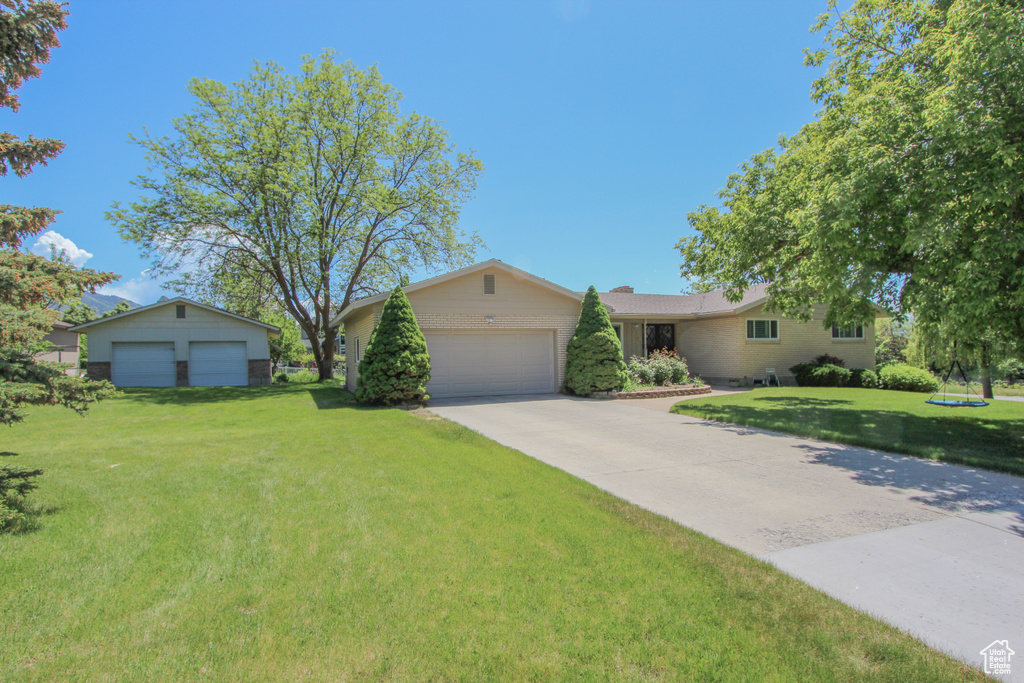 Ranch-style home featuring a front yard, driveway, and an attached garage