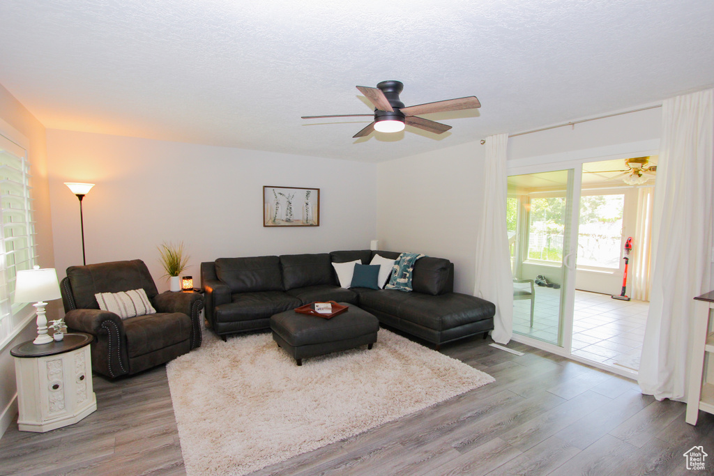 Living area featuring ceiling fan, wood finished floors, and a textured ceiling