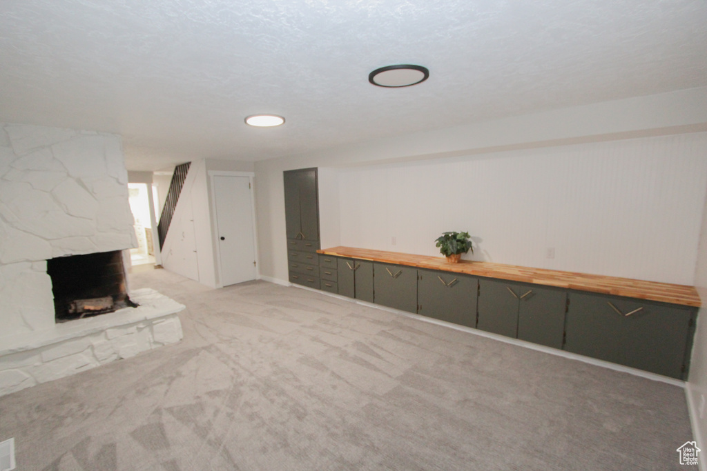 Finished below grade area featuring light carpet and a stone fireplace