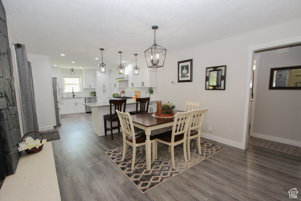 Dining area featuring dark wood-type flooring, recessed lighting, baseboards, and a chandelier