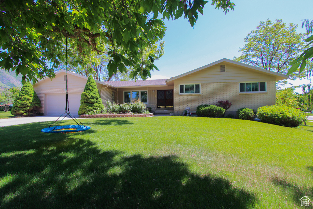 Single story home with an attached garage, a front lawn, brick siding, and concrete driveway