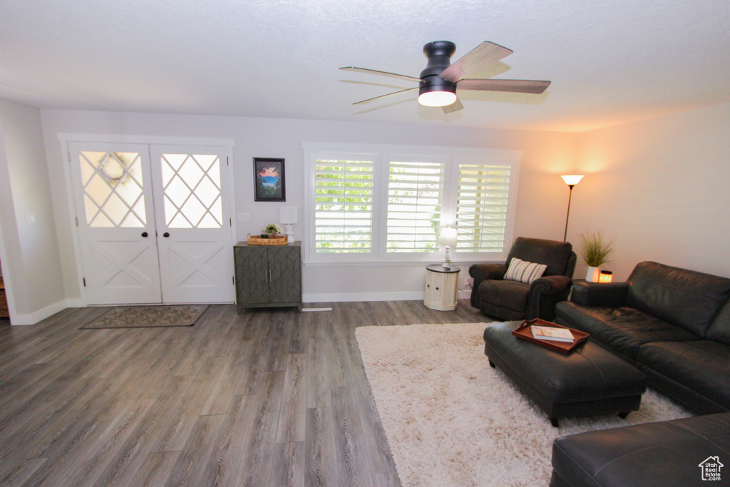 Living area with wood finished floors, a ceiling fan, and baseboards