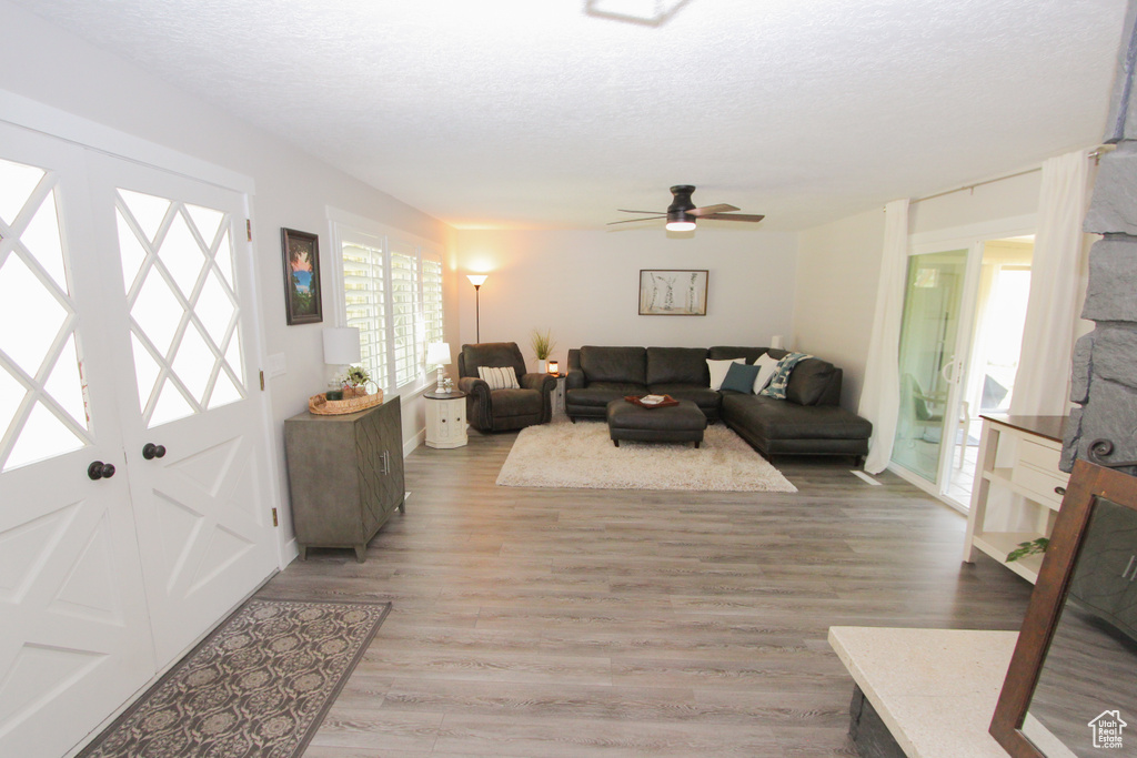 Living room featuring light wood finished floors, ceiling fan, and a textured ceiling