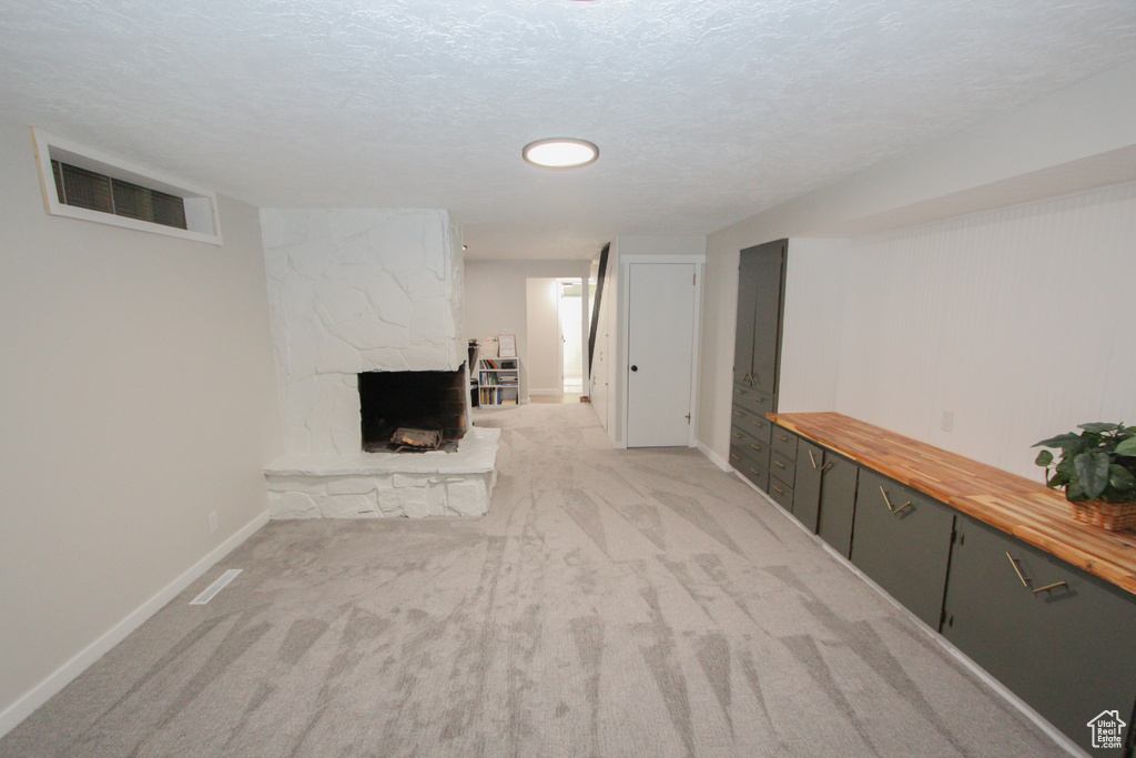 Finished basement with a stone fireplace, baseboards, and light carpet