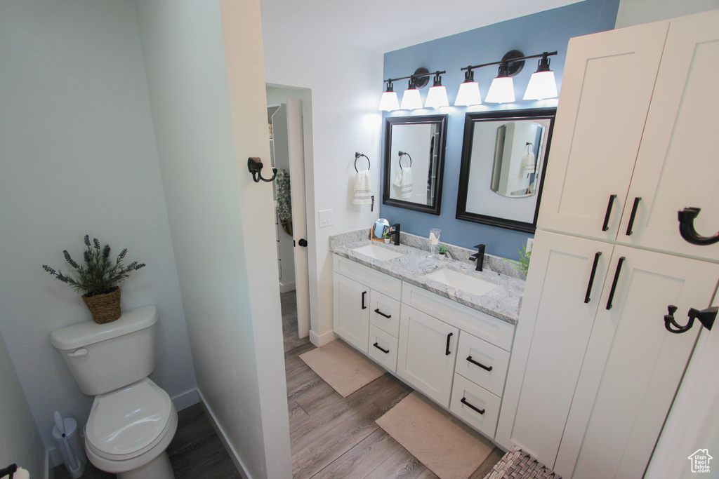 Full bathroom with wood finished floors, double vanity, toilet, and baseboards