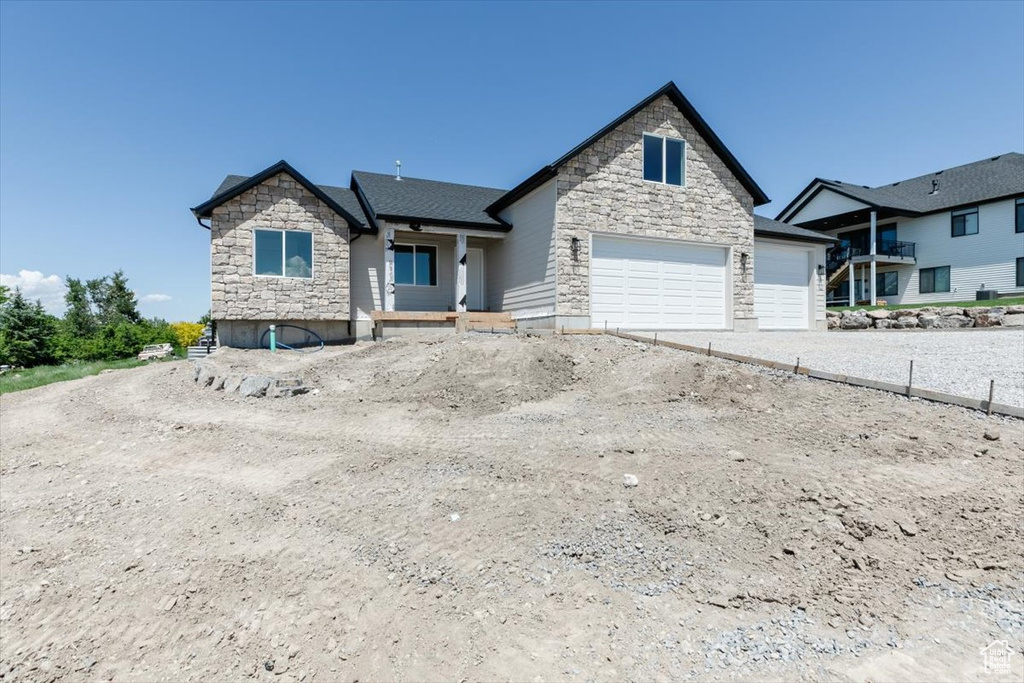 View of front of property featuring stone siding, an attached garage, and driveway