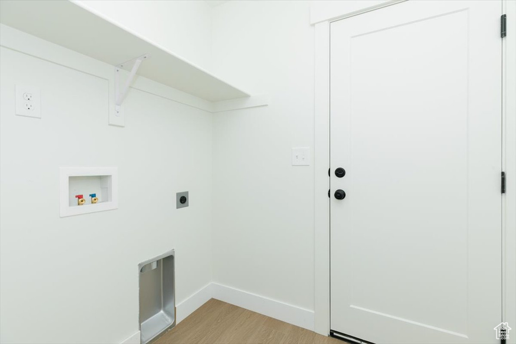 Laundry room with hookup for a washing machine, electric dryer hookup, light wood-type flooring, and baseboards