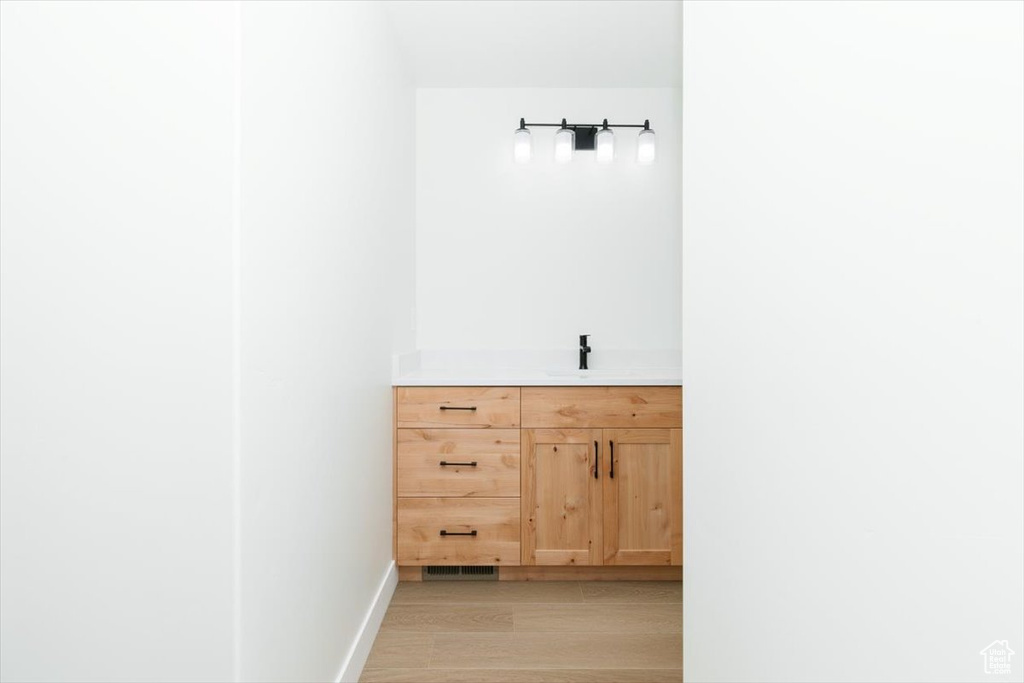 Bathroom with wood finished floors, vanity, and baseboards