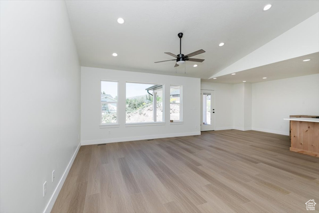 Unfurnished living room featuring vaulted ceiling, recessed lighting, baseboards, light wood-style flooring, and ceiling fan