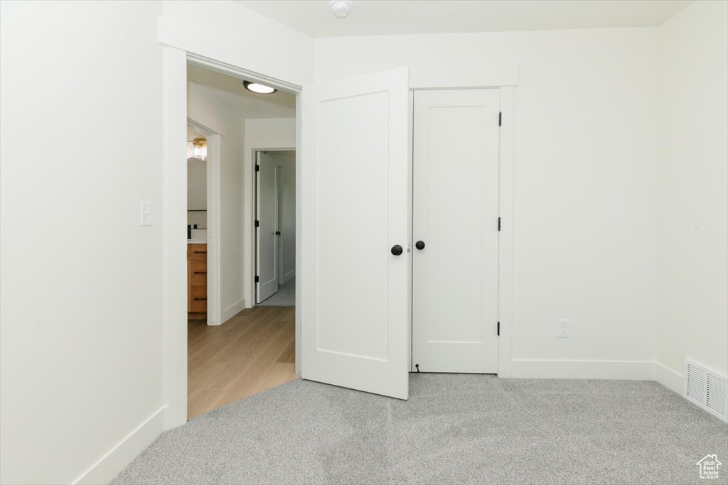 Unfurnished bedroom featuring light carpet, baseboards, and a closet