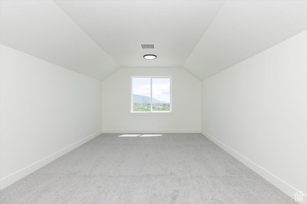 Bonus room featuring light colored carpet, lofted ceiling, and baseboards