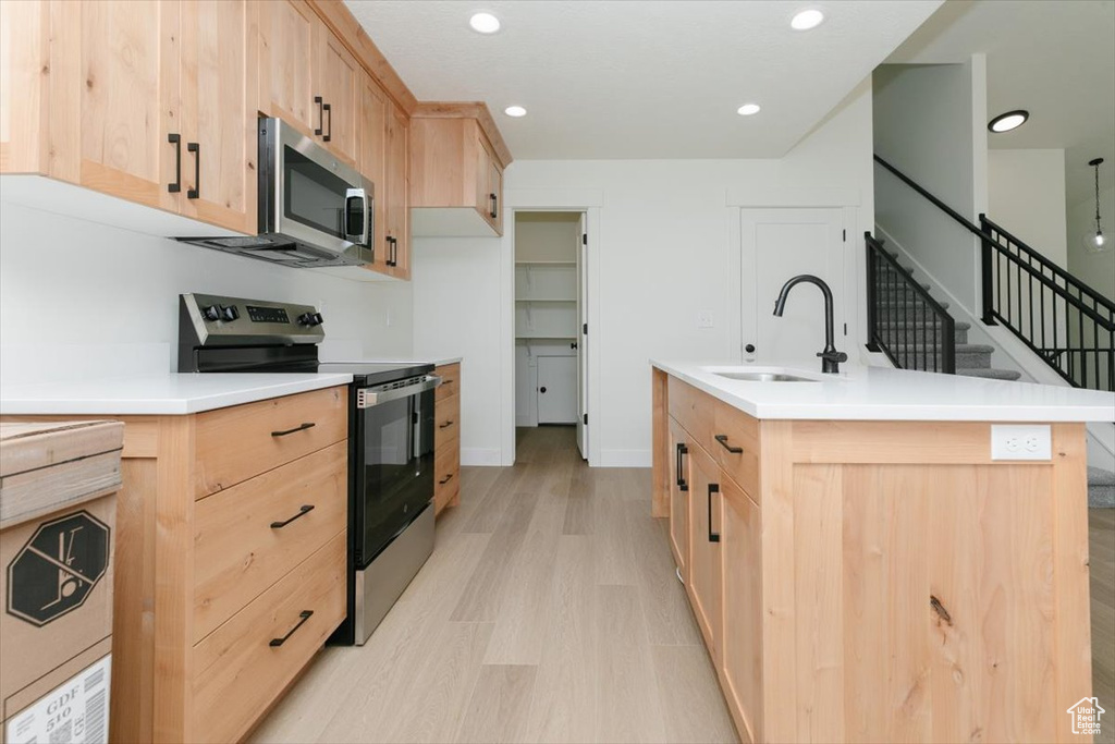 Kitchen featuring appliances with stainless steel finishes, light brown cabinets, a sink, and recessed lighting