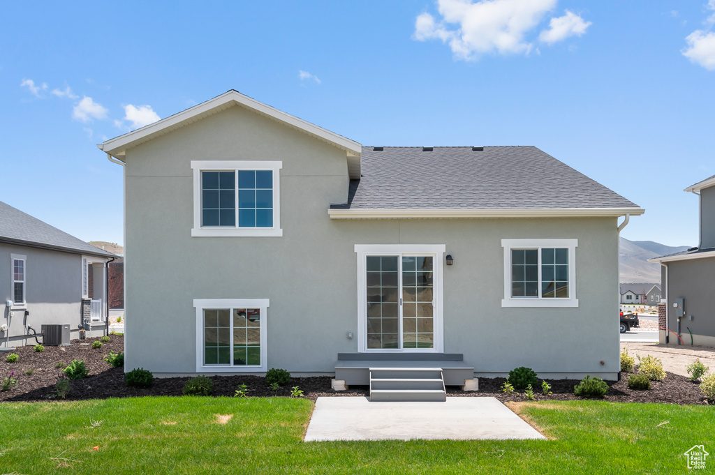 Rear view of house featuring a yard, a shingled roof, a patio area, cooling unit, and stucco siding