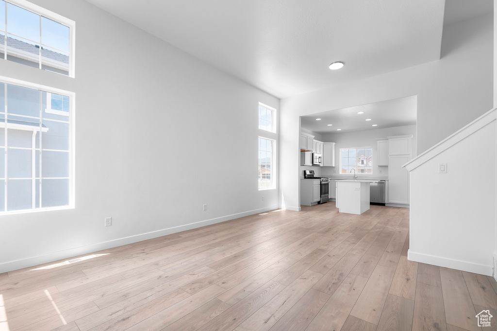 Unfurnished living room featuring light wood-style floors, recessed lighting, and baseboards