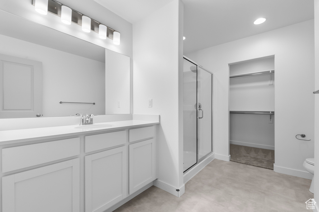 Bathroom with vanity, a stall shower, a walk in closet, toilet, and recessed lighting