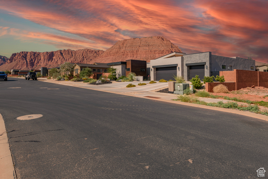 Contemporary home featuring a mountain view, an attached garage, concrete driveway, stucco siding, and a residential view