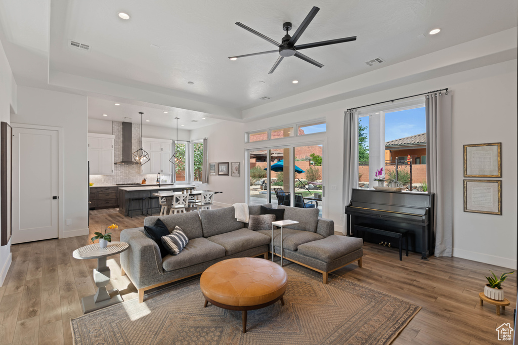 Living area featuring ceiling fan, recessed lighting, light wood finished floors, and a tray ceiling